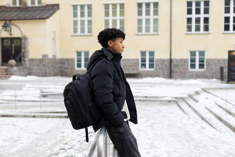 En mann med ryggsekk som går i snøen.