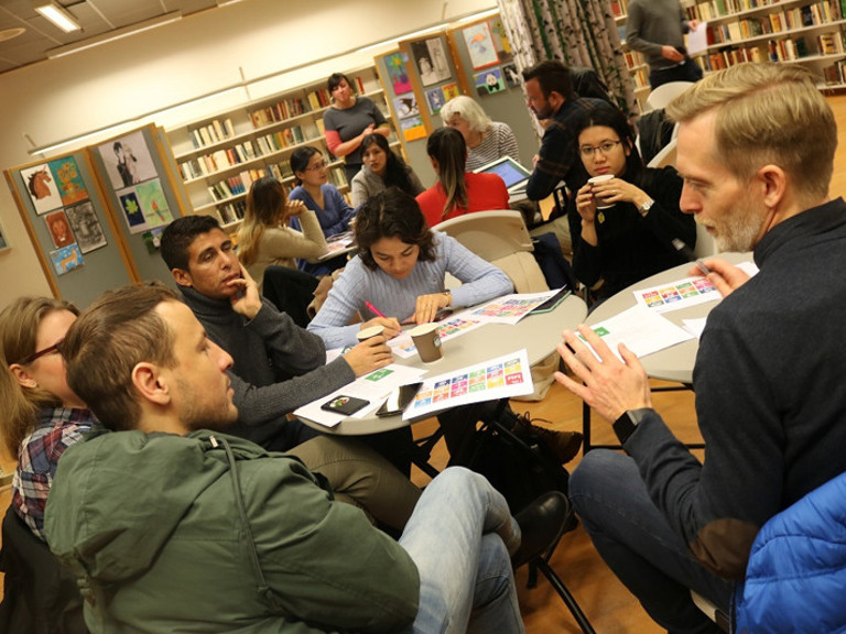 En gruppe mennesker som sitter rundt et bord i et bibliotek.